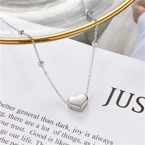 Collier cœur minimaliste en argent avec chaîne à billes sur fond décoratif chic