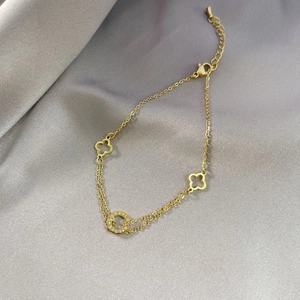 Detail der goldenen Titanstahl-Fußkette mit Kleeblatt-Anhängern und LOVE-Gravur am Ring