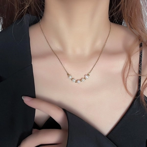 Elegant gold necklace with five freshwater pearls and metallic beads worn on neck