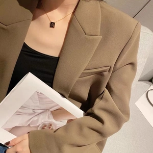 Collier élégant avec pendentif carré lettre A en or porté par un mannequin avec un blazer