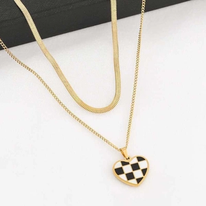 Double-layered gold herringbone necklace with black and white checkerboard heart pendant