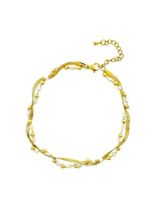 Detalle de tobillera dorada de doble capa con cadena de serpiente y perlas blancas