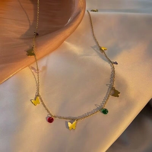 Golden butterfly necklace with colorful gemstone pendants on white satin fabric