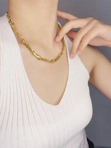Gros plan d'un collier à maillons dorés sur un mannequin portant un débardeur blanc
