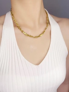 Détail d'un collier en chaîne dorée avec maillons feuilles texturés sur un mannequin