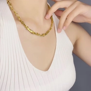 Collier fait main aux maillons tissés dorés et torsadés porté par un mannequin féminin