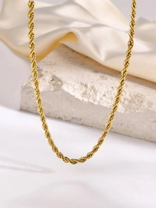 Close-up detail of golden stainless steel rope chain necklace on elegant silk background