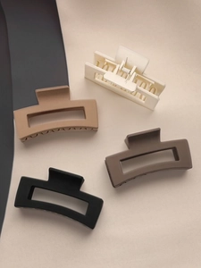 Detail of four matte rectangle hair claws in cream, tan, brown and black earth tones