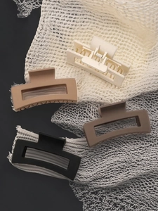 Close-up of matte rectangular hair claws in four earthy colors on a mesh background