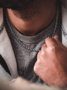 Macro shot of silver stainless steel rope chain showing dense woven texture on male neck