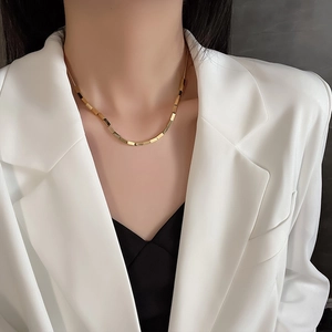Polished gold titanium steel geometric bamboo link necklace worn by a female model