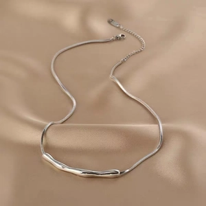 Detailed shot of irregular silver necklace with curved pendant on champagne satin