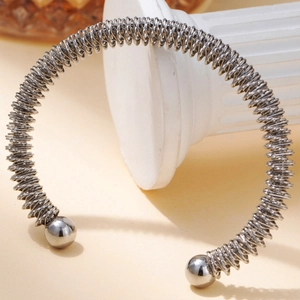 Detail eines silbernen Edelstahl-Armreifs mit Spiraldraht und glänzenden Endkugeln