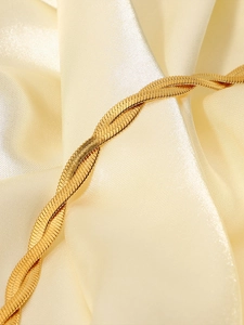 Macro shot of gold plated snake bone chain showing delicate fish scale texture on satin