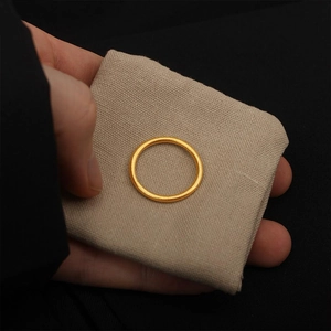 Dettaglio dell'anello in acciaio dorato opaco con elegante trama in metallo spazzolato