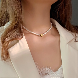 Elegant heart pendant necklace with white pearls on a model wearing a white blazer
