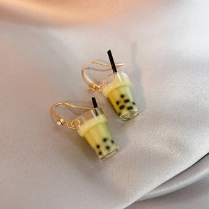 Detail of creative milk tea cup earrings with gold hooks and green matcha liquid filling
