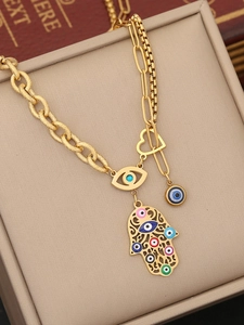 Macro view of gold Hamsa hand necklace with colorful evil eye charms and heart detail