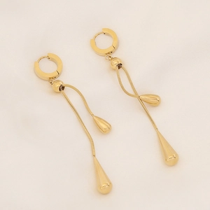 Elegante goldene Tropfen-Ohrringe mit Quasten und glänzendem Finish auf cremefarbenem Stoff