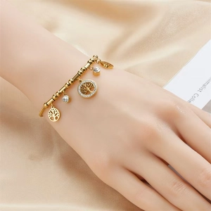 Detail eines goldenen Lebensbaum-Armbands mit funkelnden Strasssteinen am Handgelenk