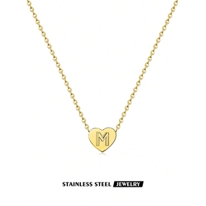 Close-up of golden stainless steel heart pendant with engraved letter M on an O-chain