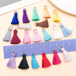 Détail de mini glands colorés avec anneaux dorés pour la création de bijoux DIY