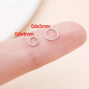 Nahaufnahme von 0,6x4mm und 0,6x5mm Edelstahl-Binderingen am Finger zum Größenvergleich