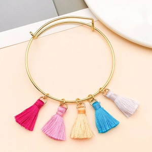 Détail d'un bracelet en fil doré avec cinq mini pompons colorés pour bijoux artisanaux