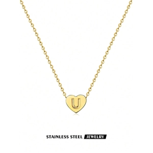 Detailed close-up of golden stainless steel heart pendant with engraved letter U