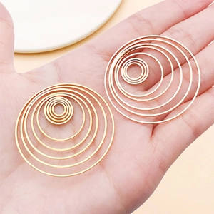 Handheld view of large multi-layer concentric gold circles earrings showing size and scale