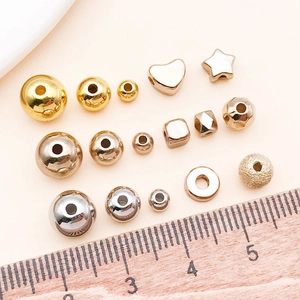 Sortierte Gold- und Silber-DIY-Perlen in verschiedenen Formen mit einem Holzlineal