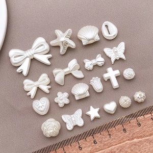 Vista macro di ciondoli in perle ABS crema a forma di fiocco e cuore per gioielli DIY