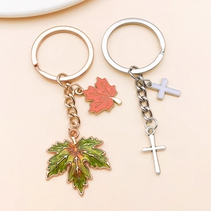 Detail of rose gold maple leaf and silver cross metal pendants for DIY keychains