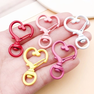 Moschettoni colorati a forma di cuore tenuti in mano per mostrare dimensioni e dettagli