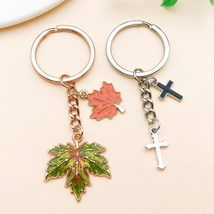 Detail of DIY maple leaf and cross keychains with colorful enamel coating and metal finish
