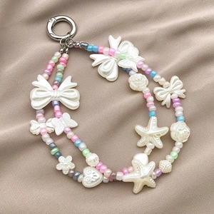 Dettaglio di ciondolo in perle macaron colorate con fiocchi acrilici su tessuto beige