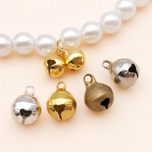 Makroaufnahme bunter 6-10mm Kupferglocken für DIY-Schmuck auf rosa Hintergrund
