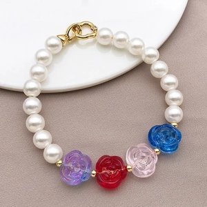 Close-up of white pearls and glass rose beads on a bracelet with gold heart clasp