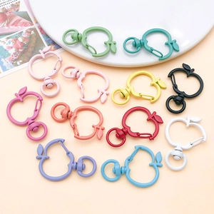 Colorful apple-shaped alloy lobster clasps and keychains on a warm orange surface