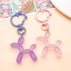 Detail of glittery resin balloon dog keychains with unique apple-shaped metal clasps