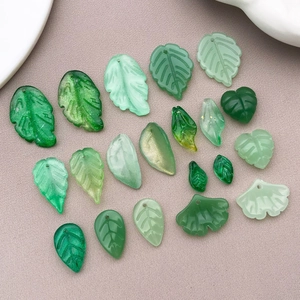 Flat lay of colorful glass leaf pendants with intricate veins for DIY jewelry making