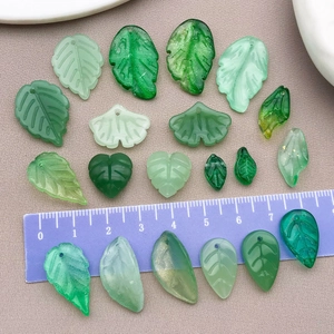 Macro detail of assorted green resin leaf beads with scale ruler for jewelry DIY