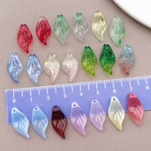 Detailed view of 20mm leaf-shaped glass beads in vibrant colors with ruler for scale