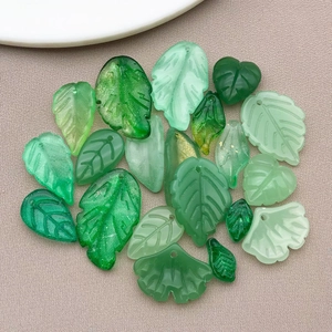 Macro shot of assorted translucent green glass leaf charms with detailed vein textures