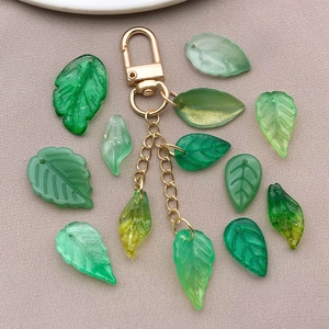 Detailed flat lay of golden D-ring keychain with translucent green leaf resin charms
