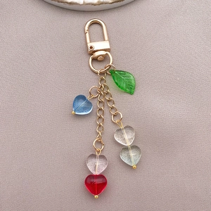 Detail of 10mm candy-colored glass heart beads and green leaf charm with gold metal clasp