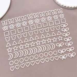 Flat lay of white faux pearl charms in heart and moon shapes for DIY crafts and nail art