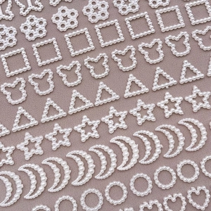 Flat lay of white pearlescent hollow heart and star shaped DIY jewelry charm accessories