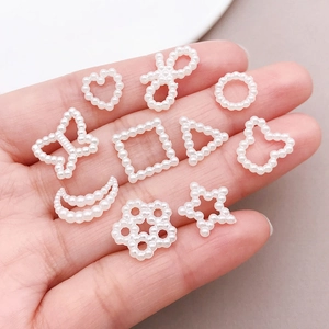 Detailed view of ten mixed white faux pearl charms in heart, moon, and bow shapes