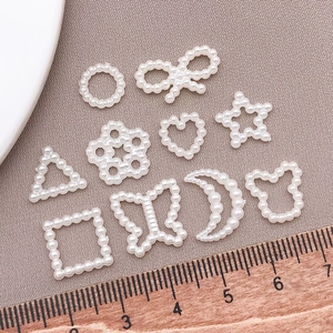 Flat lay of white faux pearl charms in heart and moon shapes with a size reference ruler